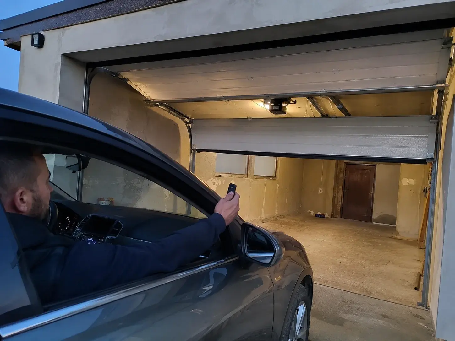 Osoba otvara garažna vrata daljinskim iz automobila