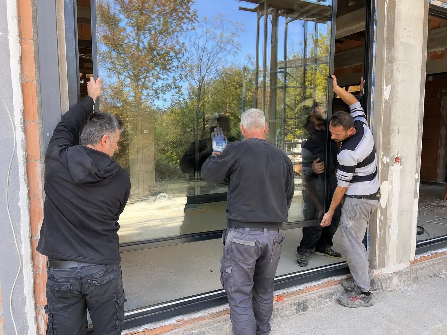 Monteri pažljivo postavljaju veliko staklo u aluminijumski ram